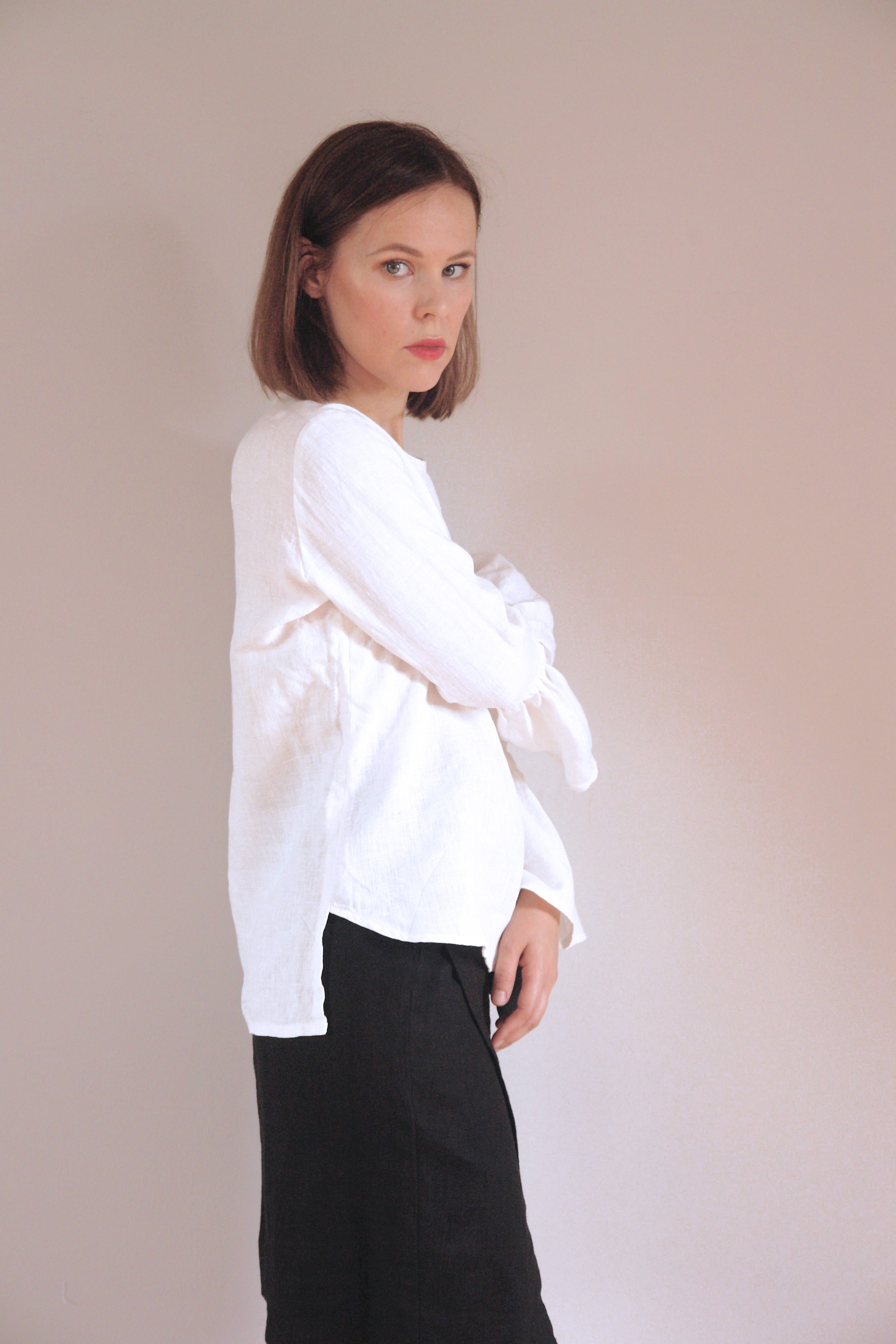 Minimalist white blouse with exaggerated ruffle sleeves, adding a touch of elegance and movement. Styled with a black skirt for a classic monochrome outfit.