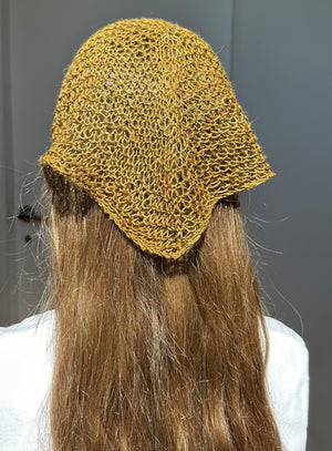 green linen knitted hat on a person with long hair against a gray background