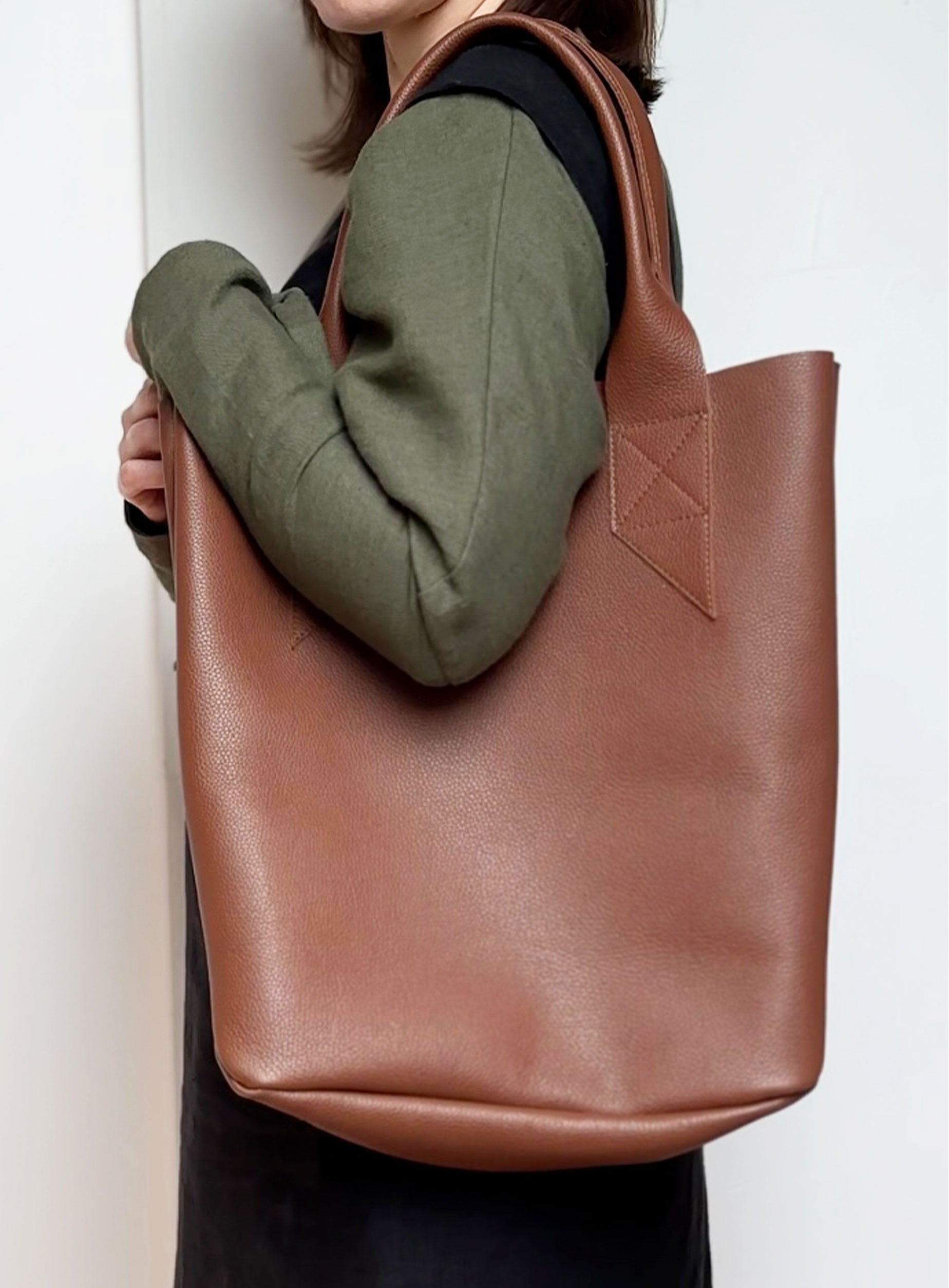 Side angle of the leather tote bag in brown, highlighting its spacious interior and sleek silhouette