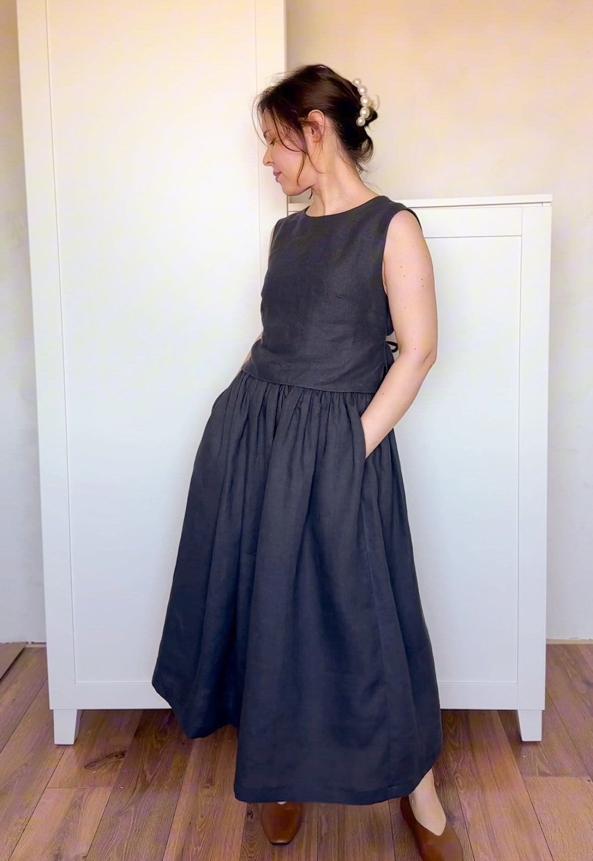 Dark charcoal linen skirt with a full, gathered silhouette and deep pockets, styled with a matching sleeveless top