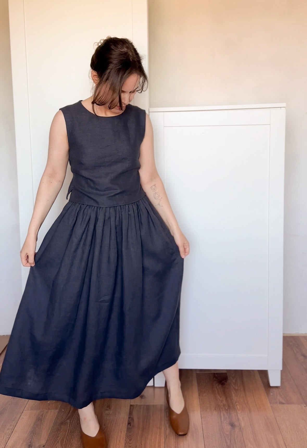 Minimalist outfit featuring a high-waisted, flowy black linen skirt paired with a sleeveless linen blouse