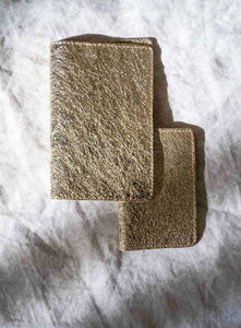 A stylish gold passport wallet designed for travelers, featuring a smooth surface and durable edges, placed on a neutral-toned backdrop