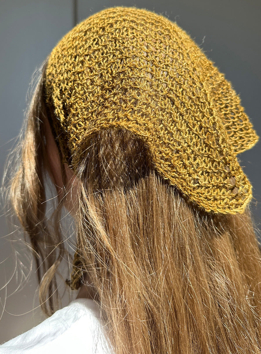 Person wearing a green linen bandana with long hair.