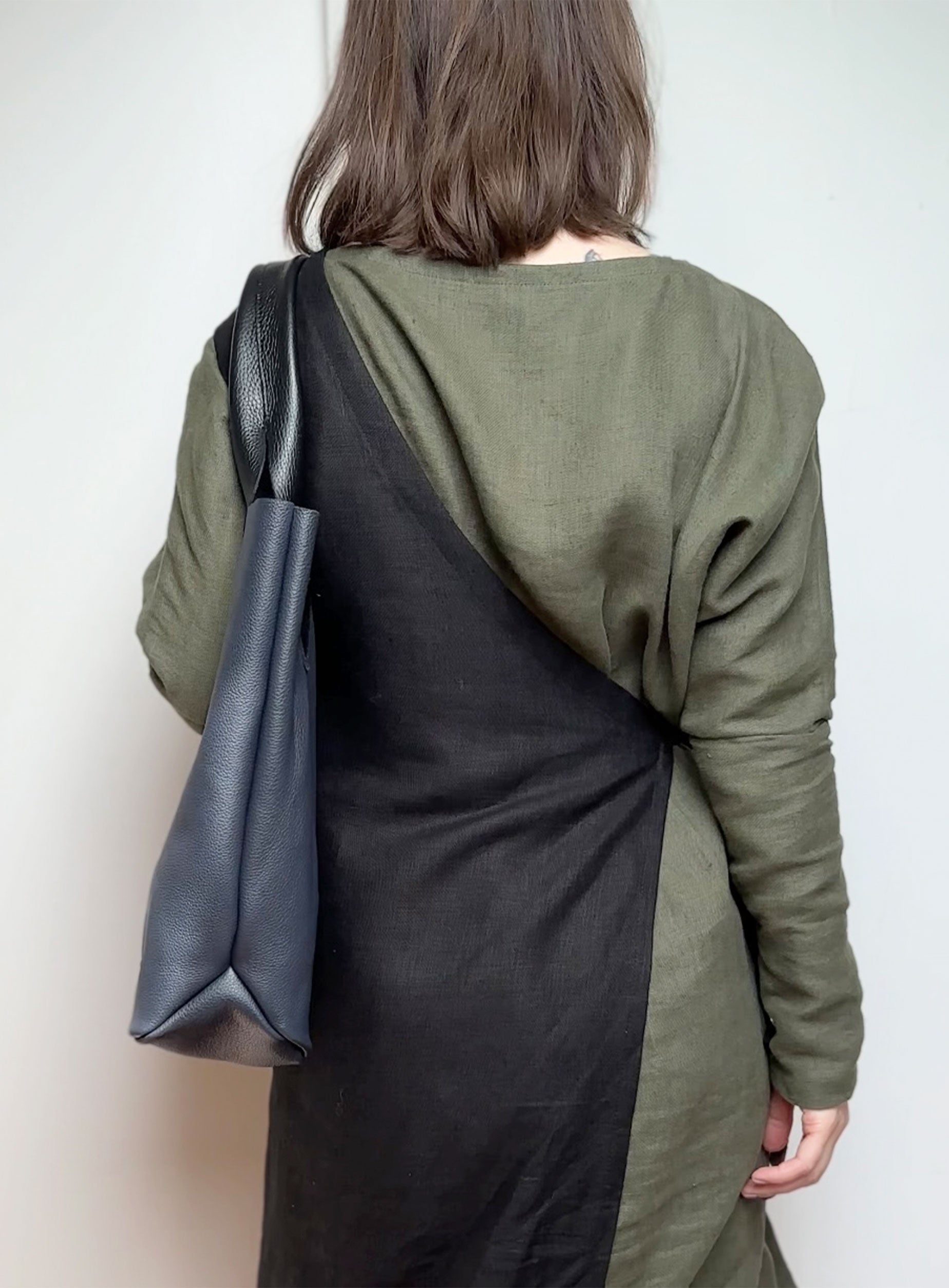 Model holding the navy blue leather tote bag by its black handles, demonstrating its size and fit.