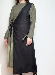 Front view of the Linen Apron Dress in black, showcasing its minimalist design and adjustable straps