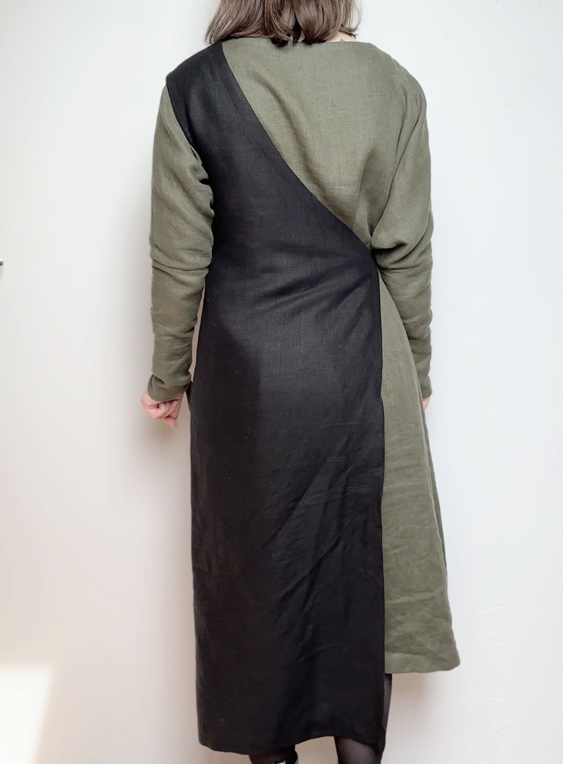 Back view of the Linen Apron Dress in black, highlighting the cross-back strap design and knee-length cut.