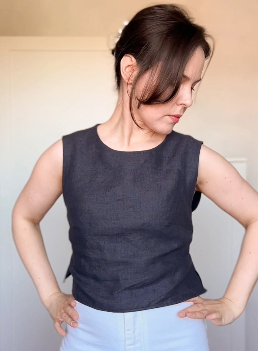 Elegant handmade linen top shown from the back, highlighting a subtle ruffle and tie accent at the waist