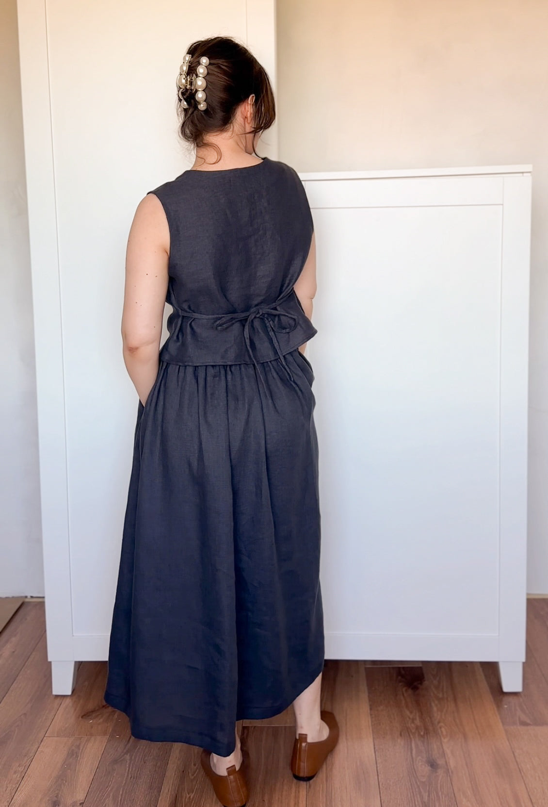 Midi-length black linen skirt with a voluminous A-line shape and subtle pleats, worn with simple leather flats