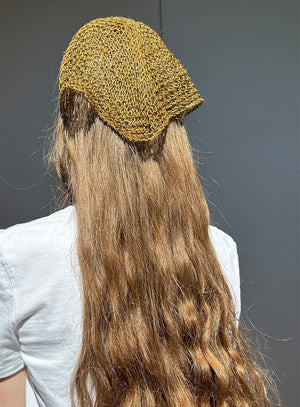 Person wearing a green knitted headband with long hair against a gray background