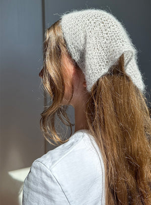 Person wearing a knitted headband with a neutral background