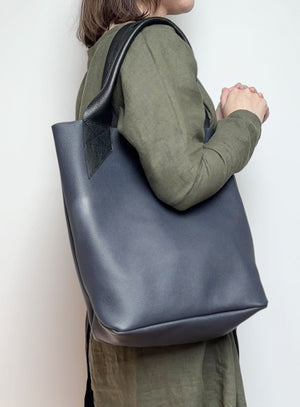 Side angle of the navy blue leather tote bag, highlighting its soft texture and structured silhouette