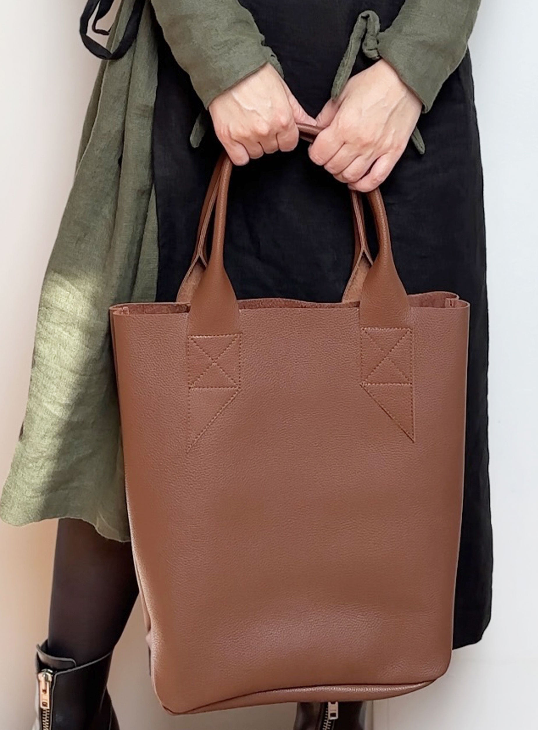 Model holding the leather tote bag in vegetable tanned, demonstrating its size and everyday usability.