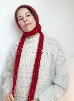 Side view of a woman modeling a red sequin bonnet tied under the chin, styled for fairy tale-inspired outfits, ideal for fall and winter fashion lovers.