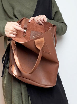 Flat lay of the leather tote bag in brown showing its dimensions and minimalist design