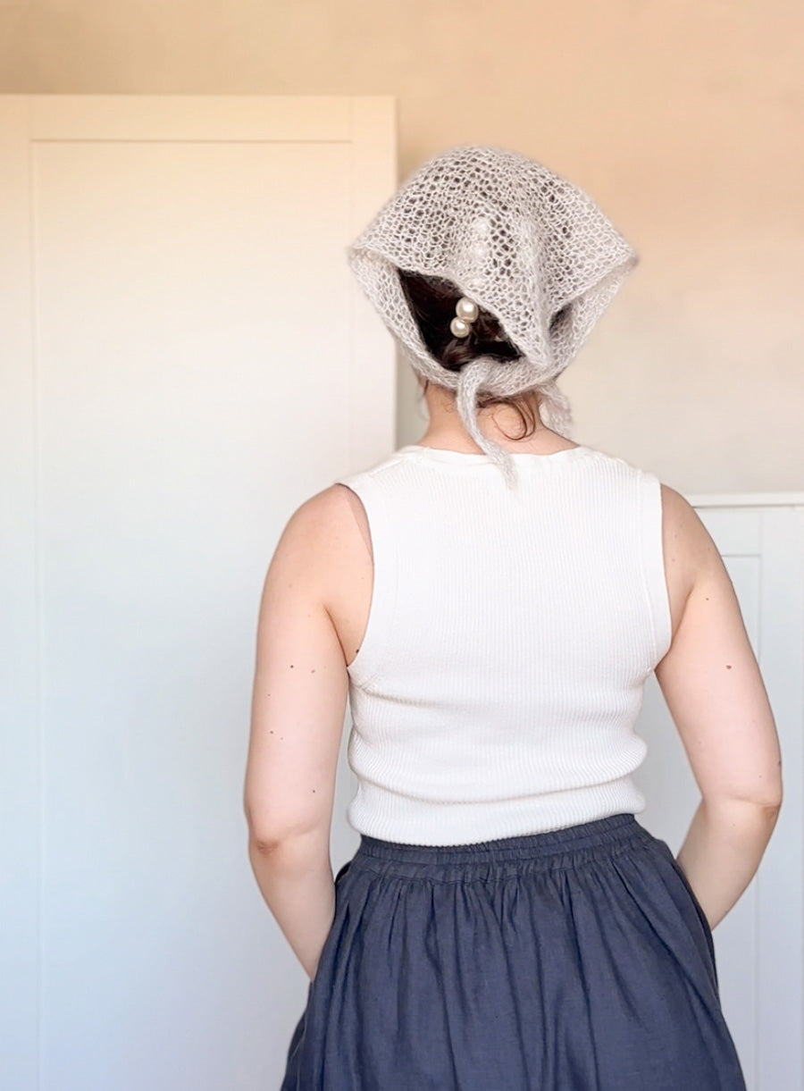Person wearing a textured headscarf with a neutral background