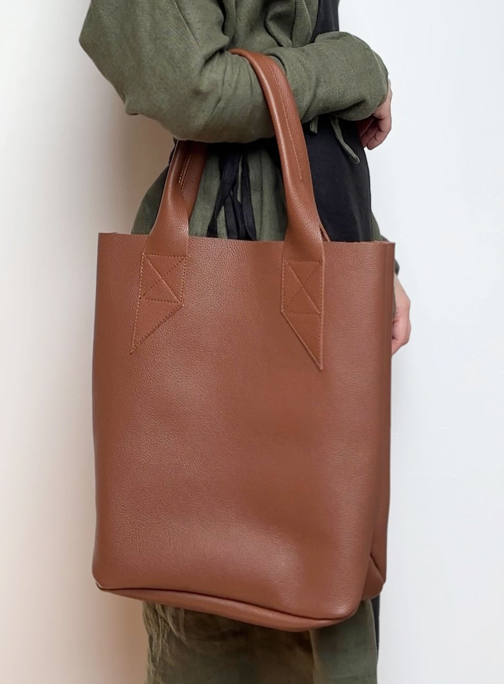 Front view of the leather tote bag in brown, showcasing its minimalist design and sturdy handles