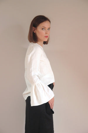 Chic and airy white linen top with long flared sleeves, perfect for a sophisticated yet effortless outfit. The natural fabric and timeless design make it a wardrobe staple.